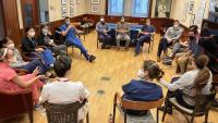 Large group of fellows sit in a circle having a meeting